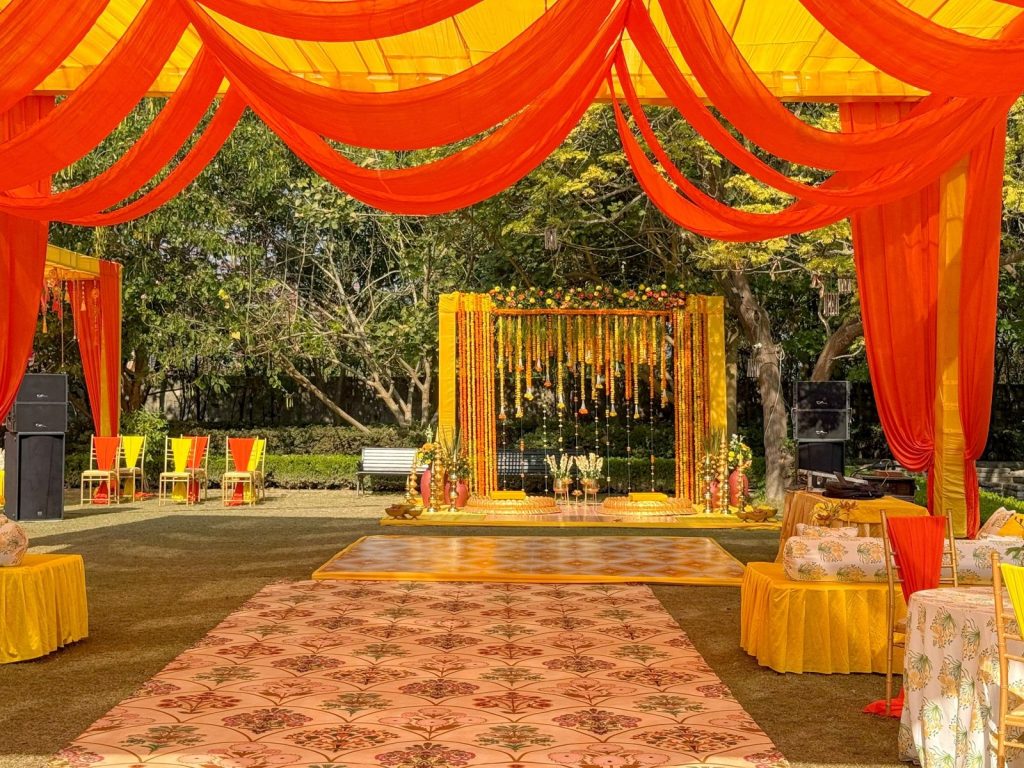 Orange drapes frame the patterned aisle leading to the haldi stage.