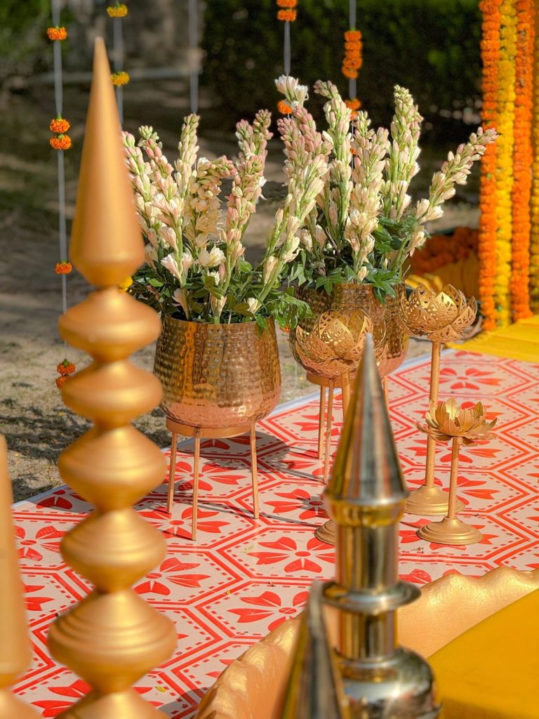 Flowers, textured vessels and lotus accents beside the haldi stage.