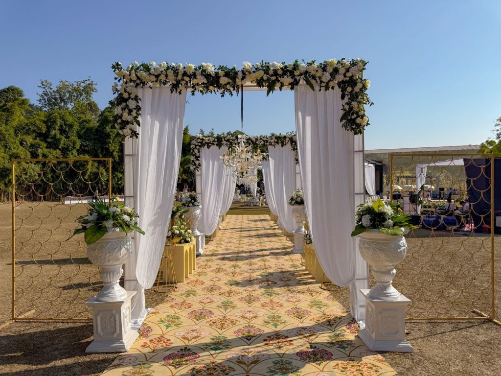 White-draped gateways and floral frames along the wedding approach.