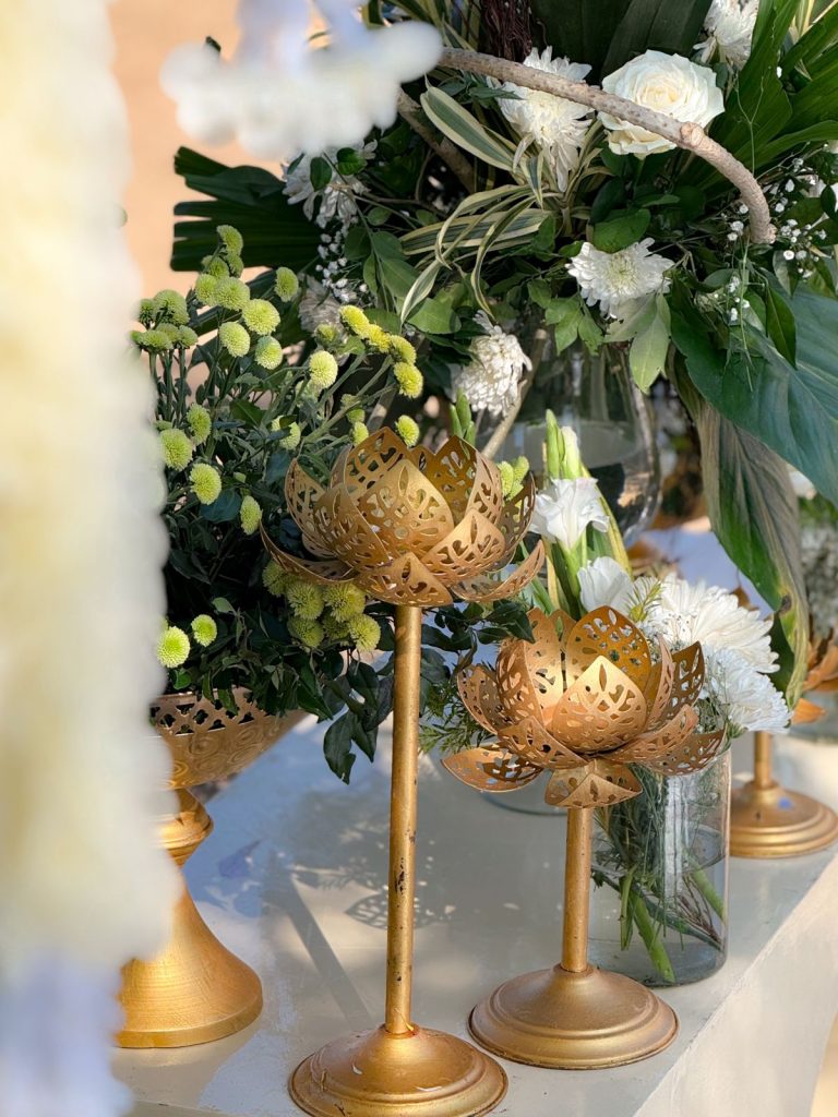 White flowers and gold-coloured lotus-shaped stands beside the stage.