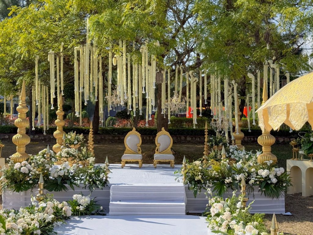 White floral strings and chandeliers hang above two gold-coloured seats on Virangana and Chirag’s wedding stage.