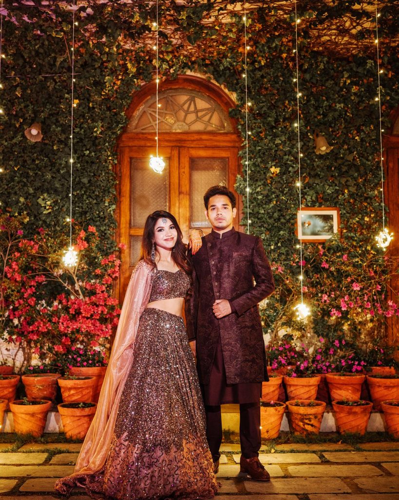 Niharika and Anirudh posing at the ivy-covered doorway of Shaheen Bagh for their engagement