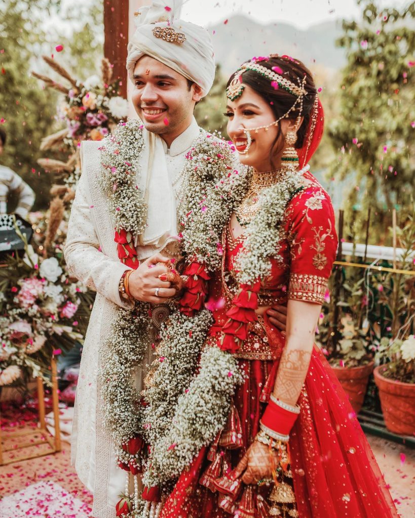 Niharika and Anirudh smiling beneath falling petals at their Shaheen Bagh wedding