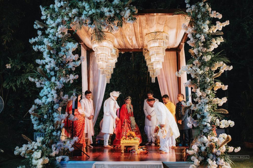 Niharika and Anirudh with family during their ceremony beneath the illuminated floral mandap