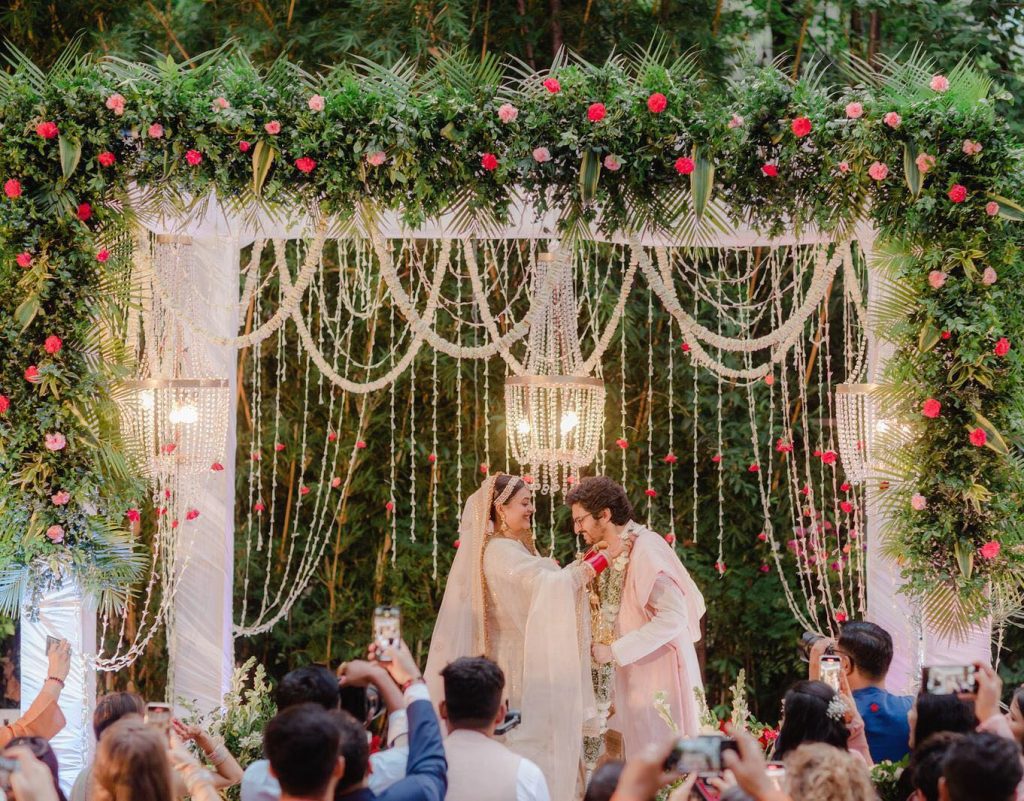 Rashi and Ayush exchanging garlands beneath a white floral mandap at Shaheen Bagh