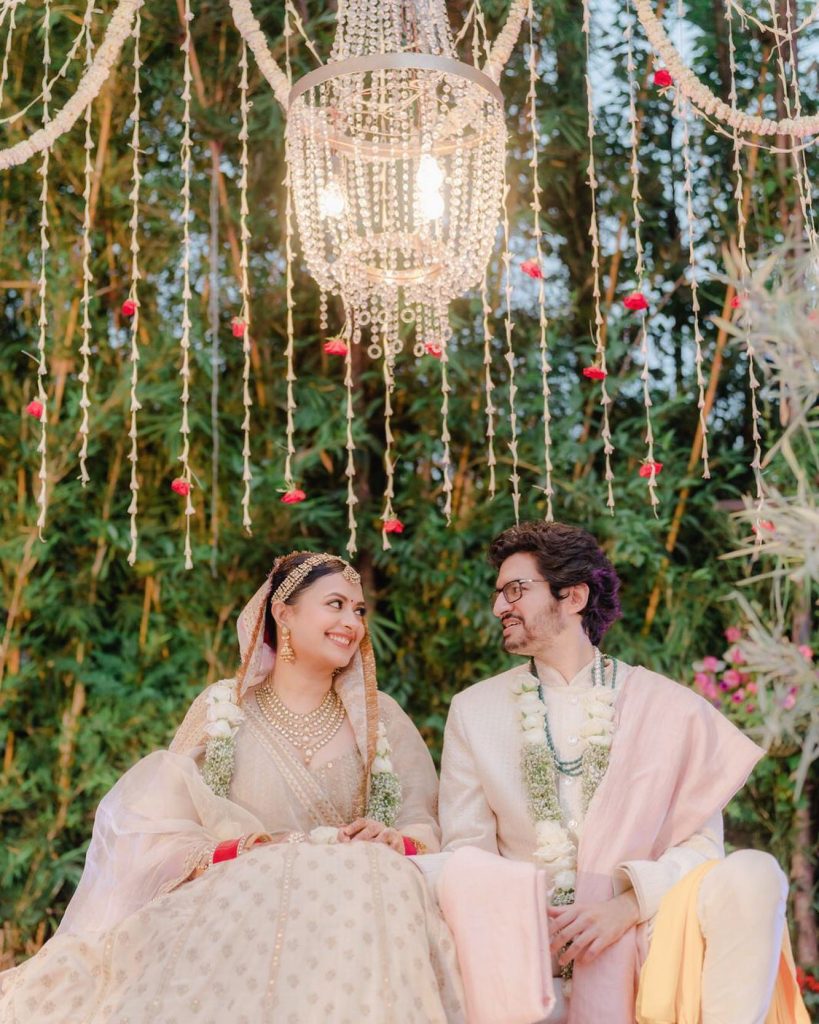 Rashi and Ayush smiling together beneath the floral canopy at Shaheen Bagh, Dehradun